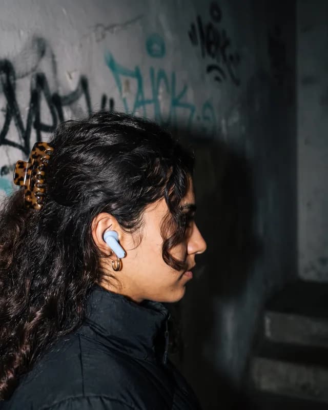 Close side view of a sky blue earbud in her ear
