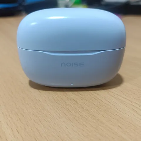 A phone photo of a sky blue earbuds case on a wooden desk